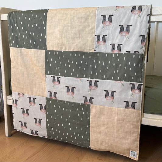 Prête à partir, Couverture de style courtepointe légèrement matelassée, vaches noires et blanches.  Endos doux en minky vert olive