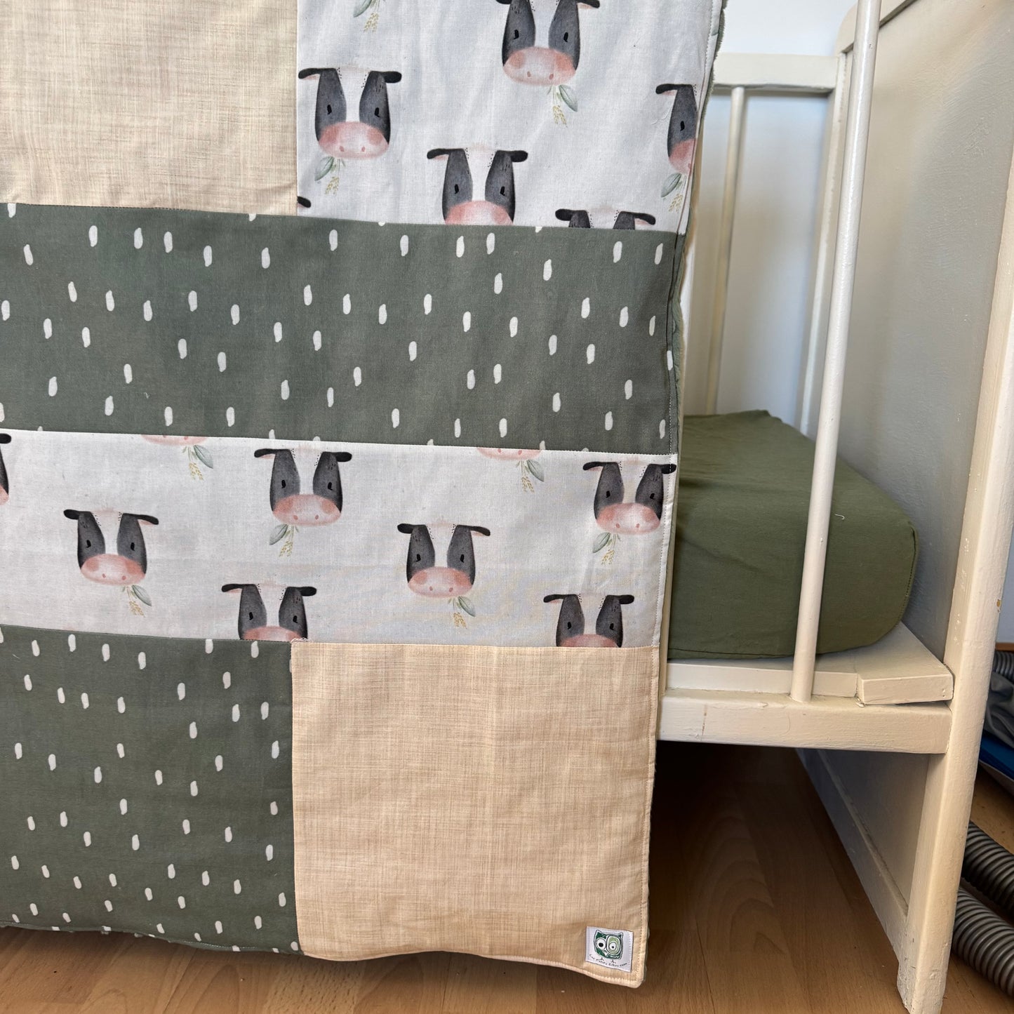 Prête à partir, Couverture de style courtepointe légèrement matelassée, vaches noires et blanches. Endos doux en minky vert olive