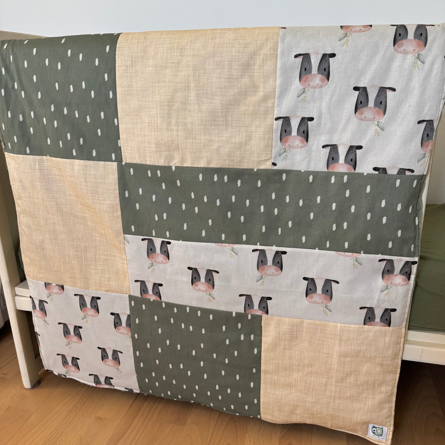 Prête à partir, Couverture de style courtepointe légèrement matelassée, vaches noires et blanches. Endos doux en minky vert olive