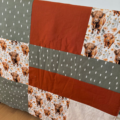 Prête à partir, Couverture de style courtepointe légèrement matelassée, vaches highland fleurie.  Endos doux en minky orange