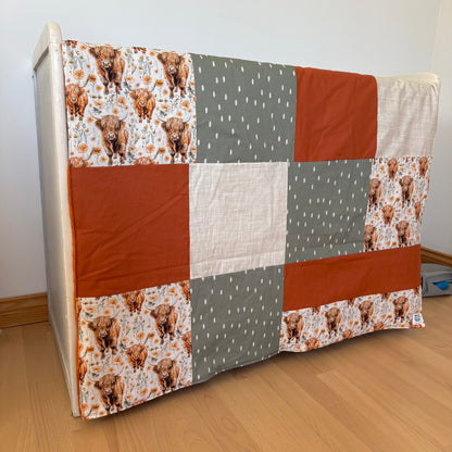 Prête à partir, Couverture de style courtepointe légèrement matelassée, vaches highland fleurie.  Endos doux en minky orange