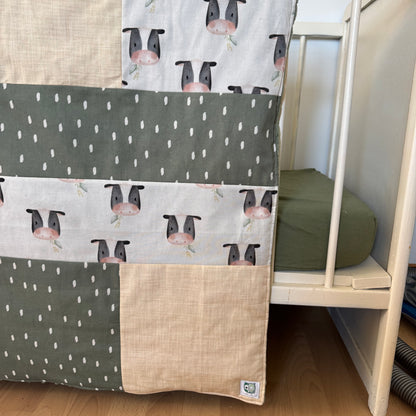 Prête à partir, Couverture de style courtepointe légèrement matelassée, vaches noires et blanches.  Endos doux en minky vert olive
