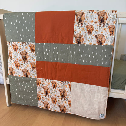 Prête à partir, Couverture de style courtepointe légèrement matelassée, vaches highland fleurie.  Endos doux en minky orange