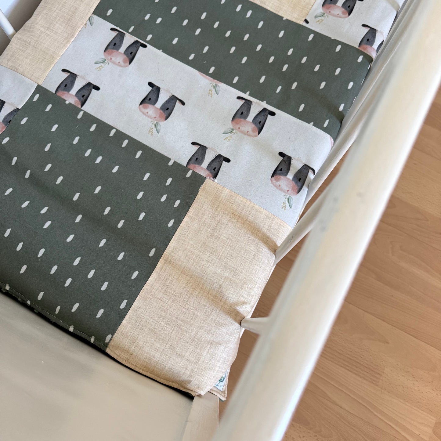 Prête à partir, Couverture de style courtepointe légèrement matelassée, vaches noires et blanches.  Endos doux en minky vert olive