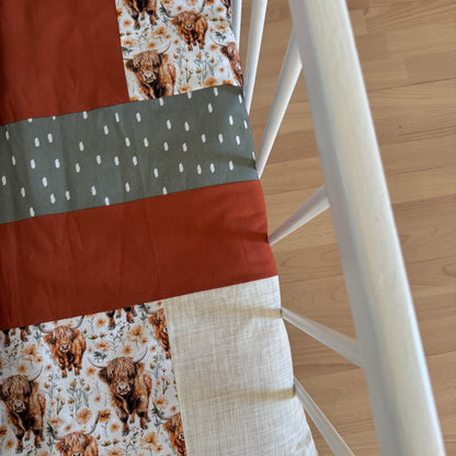 Prête à partir, Couverture de style courtepointe légèrement matelassée, vaches highland fleurie.  Endos doux en minky orange